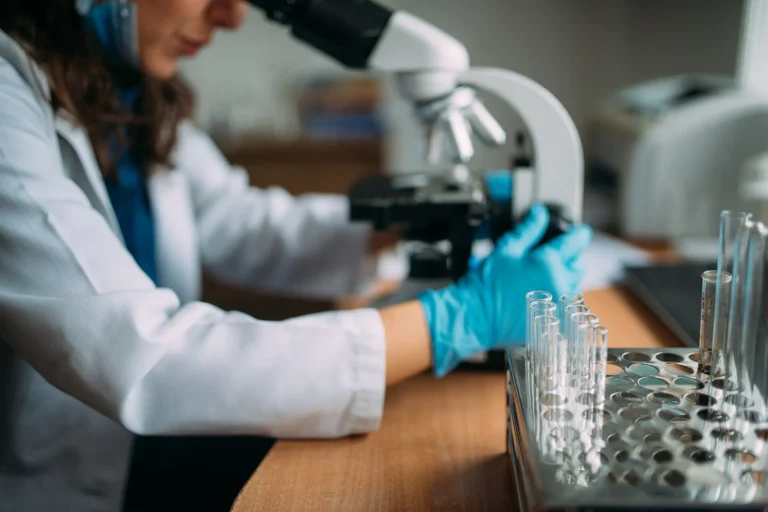 Missing the First Cases: How Surveillance Gaps Delay Outbreak Response A laboratory doctor examining samples through a microscope